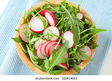 bowl of arugula and radish salad on blue place mat - Powered by Shutterstock