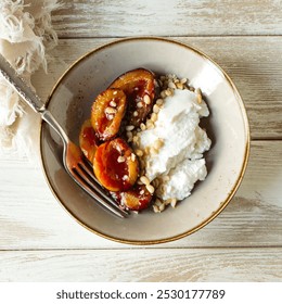 bowl of baked plums with ricotta cheese and pine nuts on light table