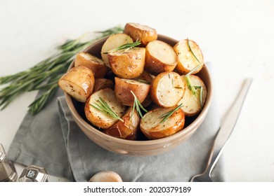 Bowl with baked potatoes on white background