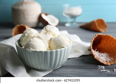 Bowl with balls of ice cream and desiccated coconut on grey wooden table