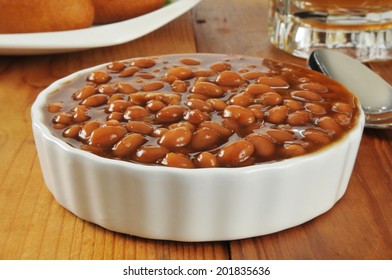 A Bowl Of Barbecue Baked Beans On A Wooden Table