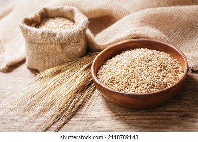 bowl of barley grains on a wooden table - Shutterstock ID 2118789143
