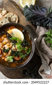 A Bowl Of Bean Soup With Kale On The Table