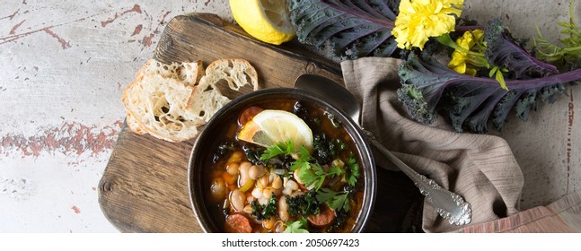 Bowl Of Bean Soup With Kale On A Wooden Board