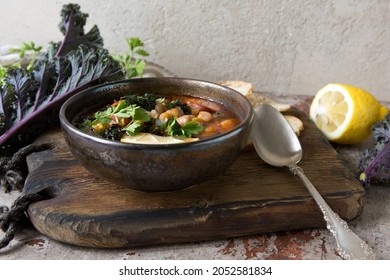 A Bowl Of Bean Soup With Kale On The Table