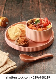 A Bowl Of Beef Soup With Some Vegetables Such As Red Bean, Sliced Carrots, Potatoes, And Tomato. It Served With Chips Made From Nuts Called Melinjo