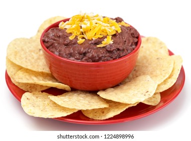 A Bowl Of Black Bean Dip With Chips On A White Background