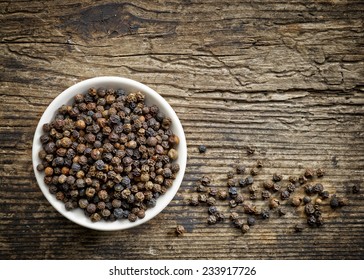 Bowl Of Black Pepper On Old Wooden Table