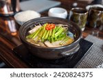 A bowl of blowfish soup with water parsley topping, served in a clay pot