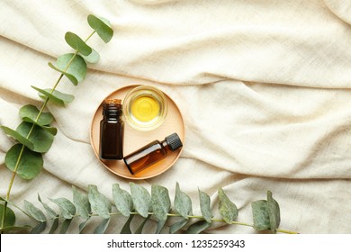 Bowl and bottles of eucalyptus essential oil on light cloth