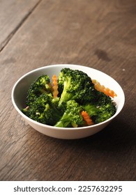 bowl of broccoli and carrot on wooden table - Shutterstock ID 2257632295