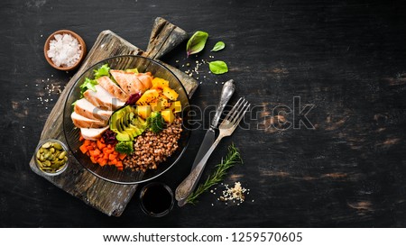 Bowl Buddha. Buckwheat, pumpkin, chicken fillet, avocado, carrots. On a black background. Top view. Free space for your text.