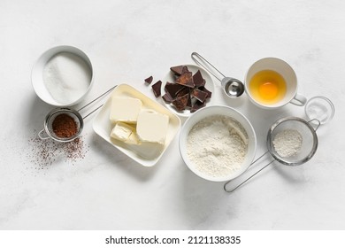 Bowl with butter and ingredients for preparing chocolate brownie on white background - Shutterstock ID 2121138335