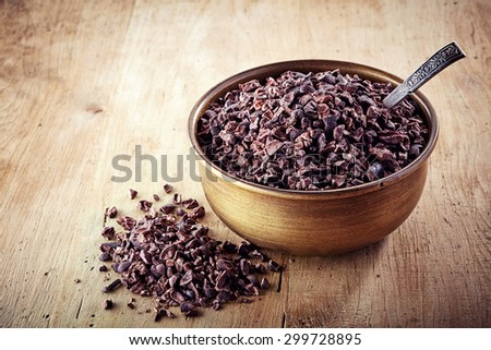 Bowl of cacao nibs on wooden background