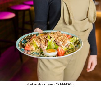 Bowl Of Caesar Salad Served In A Blue Bowl By Waiter In Resturant Or Diner. Healthy Dinner, Traditional Recipe. Copy Space Banner.