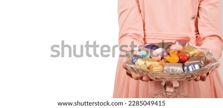 Bowl of candies,  child holding bowl of candies. Isolated white background, copy space. Offering luxury chocolate and almond dragee. Sugar feast banner concept idea. Delicious assorted sweets.