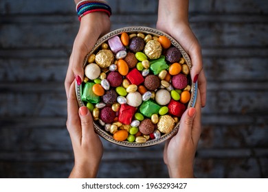Bowl of candies and chocolate at the hands of two women. Seker bayrami. Many colorful treats . 