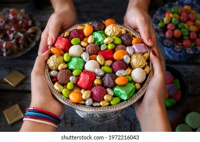 Bowl of candies and chocolate at the hands of two women. 