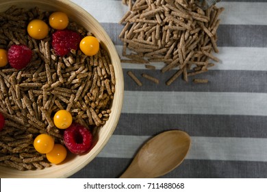 Bowl of cereal bran stick with golden berries and raspberries on table - Powered by Shutterstock