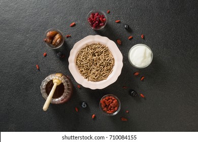 Bowl of cereal bran stick, yogurt, honey and dried fruits on black background - Powered by Shutterstock