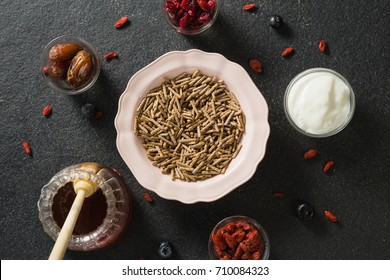 Bowl of cereal bran stick, yogurt, honey and dried fruits on black background - Powered by Shutterstock