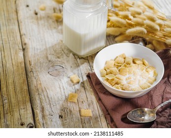 A Bowl With Cereal Pads Filled With Milk, A Jug Of Milk, A Bunch Of Cereals On A Wooden Background. Solar Lighting. Fast Breakfast Cereals, Organic Food, Healthy Nutrition, Diet, Fitness, Baby Food.