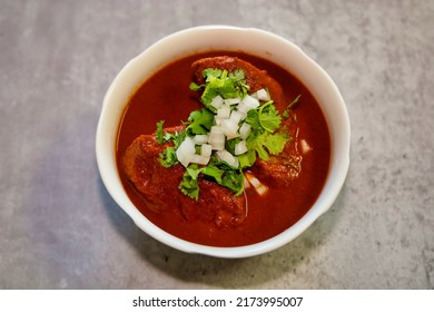 A bowl of chicken birria topped with cilantro and chopped onion.