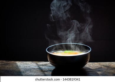 Bowl of chicken soup. steam of hot soup with smoke wood bowl on dark background.selective focus,hot food concept