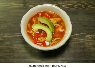 A Bowl Of Chicken Tortilla Soup With Crispy Tortilla Strips.