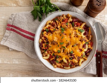 Bowl Of Chili Mac With Cheddar Cheese On A Rustic Wooden Table.  Overhead View With Copy Space