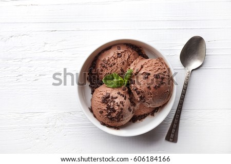 Bowl of chocolate ice cream on white wooden background. From top view