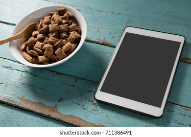 Bowl of chocolate toast crunchs with digital tablet on wooden table - Powered by Shutterstock