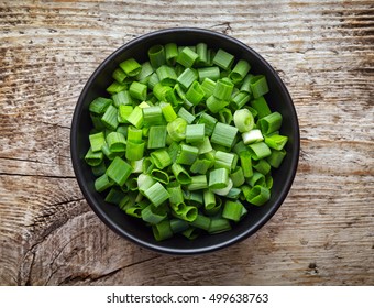 Bowl Of Chopped Spring Onions On Wooden Table, Top View