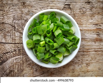 Bowl Of Chopped Spring Onions On Wooden Table, Top View