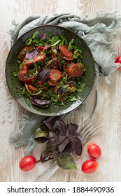 A Bowl Of Chorizo Salad On A Light Wooden Table