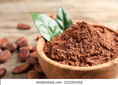 Bowl with cocoa powder on wooden table, closeup. Space for text