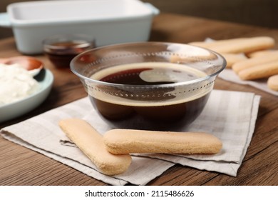 Bowl of coffee and savoiardi biscuit cookies on wooden table. Making tiramisu cake