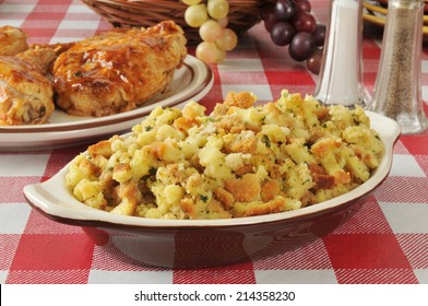 A Bowl Of Corn Bread Stuffing With Barbecued Chicken In The Background