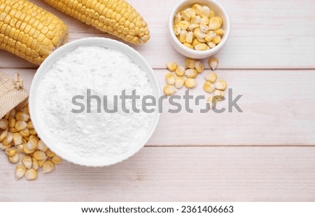 Bowl with corn starch, ripe cobs and kernels on wooden table, flat lay. Space for text