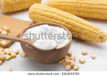 Bowl with corn starch, ripe cobs and kernels on white table