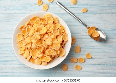 Bowl with cornflakes on white wooden background