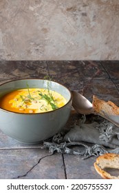 A Bowl Of Creamy Carrot Soup With Cream On The Table