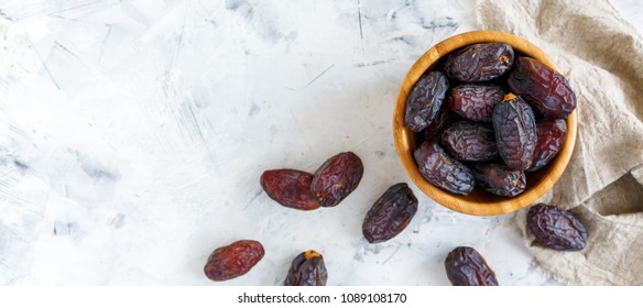 Bowl of dates and a linen cloth on a white concrete background. The view from the top.