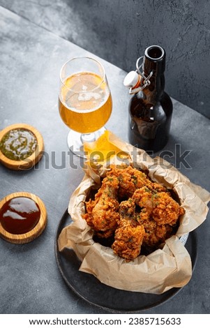 Bowl of deep fried chicken wings with bbq souse and beer on gray table vertical photo. High quality photo