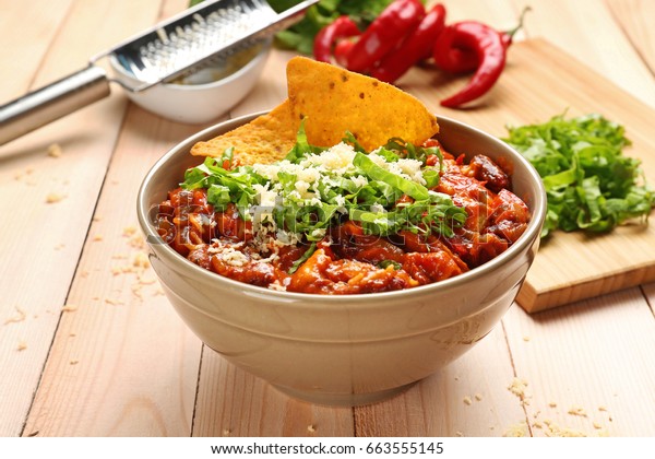Bowl with\
delicious chili turkey on wooden\
table