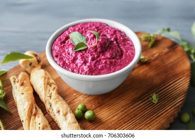 Bowl with delicious creamy beet hummus on wooden board
