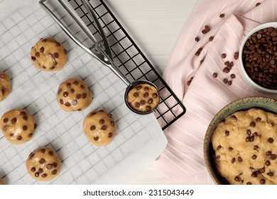 Bowl with dough and uncooked chocolate chip cookies on white wooden table, flat lay - Powered by Shutterstock