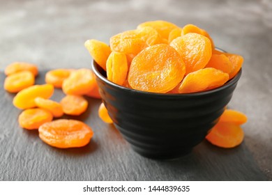 Bowl with dried apricots on grey background