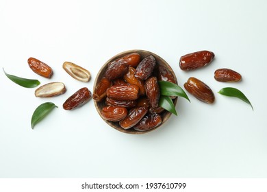 Bowl of dried dates with leaves on white background
