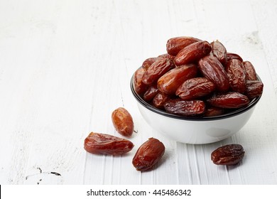 Bowl of dried dates on white wooden background